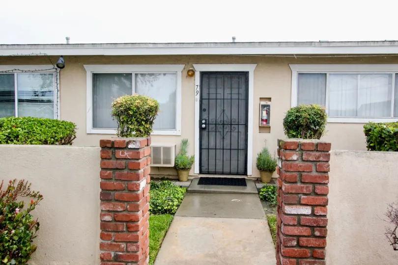 A simple bungalow in the Coco Palms community with gated front door and bricked pillars.