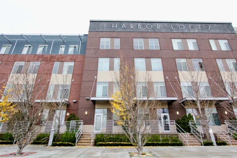 a pleasant day in the Harbor Lofts with a building that has steps in the center garden both side and trees are front