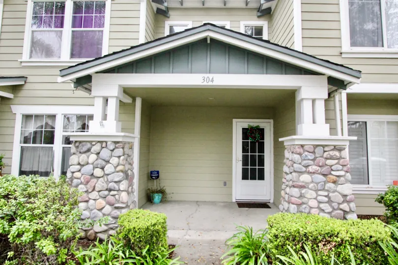 A beautiful porch entry with stone pillars and hedge in Heritage Place Bungalows in Anaheim