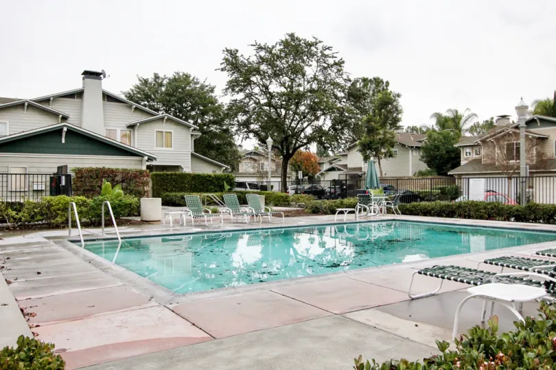 THE SWIMMING POOL WITH CHAIRS, PLANTS, TREES, BACKSIDE HOME IS THERE IN ANAHEIM CITY