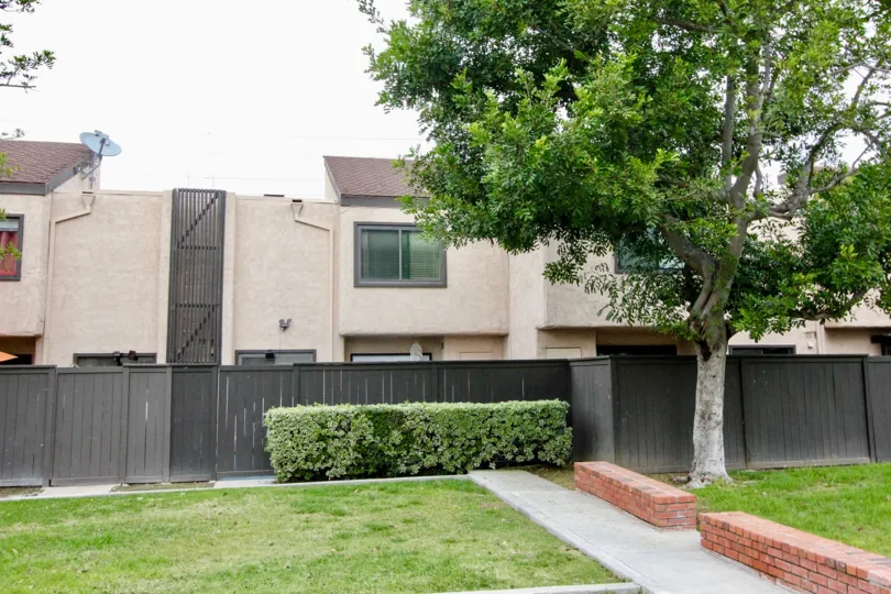 A view of units from the street showing the back fence and trees on a sunny day