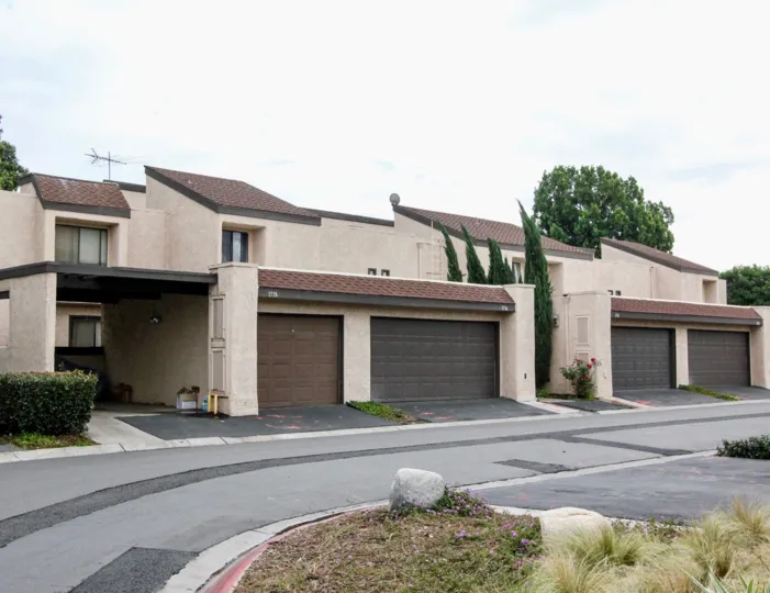 A road in the Heritage Village Townhomes with some rocks and building.