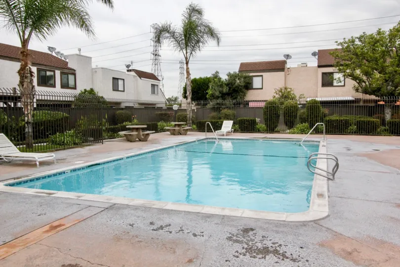 a sunny day in the Heritage Village Townhomes qithy a swimmingpool that has clear blue water and resting table