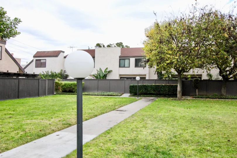 a warm day in the Heritage Village Townhomes with a building around the garden and light lamp in front and roofless top