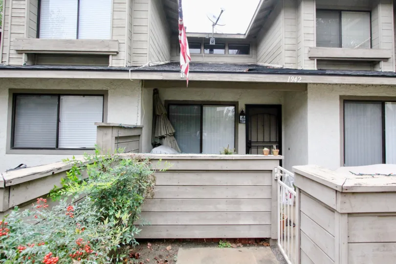A house in the Lakeview Townhomes built in 1942 with flag flying, dish fitted on the roof and flowers plant s in front of the gate