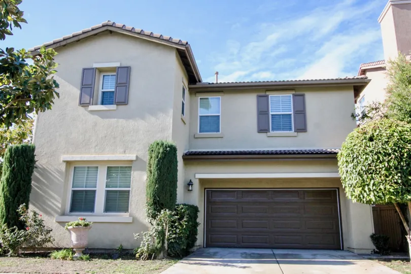 A large tan home with a brown garage in Magnolia Lane community in Anaheim, California.