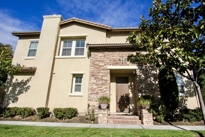 A traditional two-storey residence in Magnolia Lane community with a chimney and stone cladding.