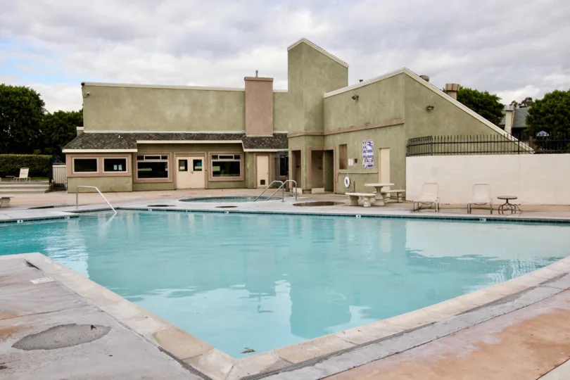 a pleasant day in the pepperwood village with a building that has swiming pool and trees on the back side