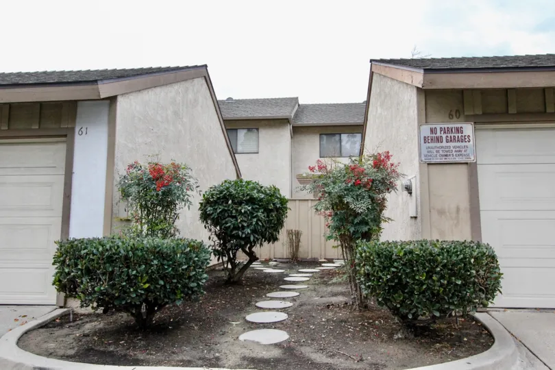A PLEASANT DAY IN THE Pepperwood Village WITH A building THAT HAS roofless top and two parking DOOR CLOSED and around the garden