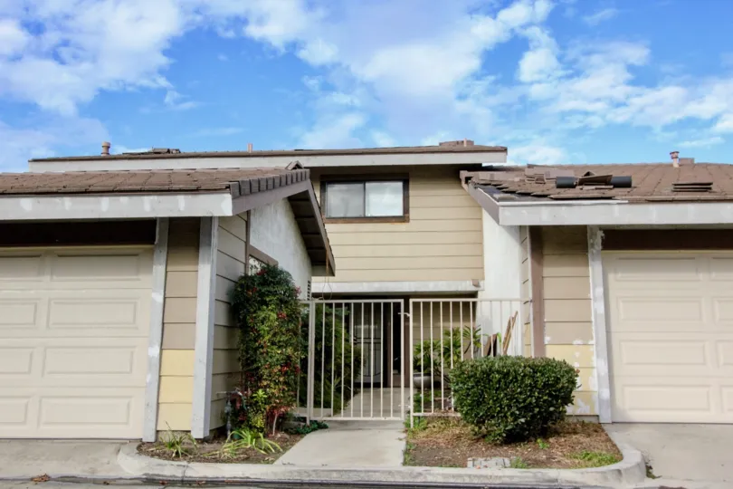 THIS SHOWS THE FRONT OF THE HOME WITH SHED ON EACH SIDE WITH PLANTS IN ANAHEIM CITY
