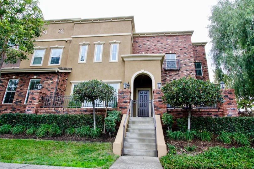 a pleasant day in the domain with house that has steps in center and stone walls and garden around