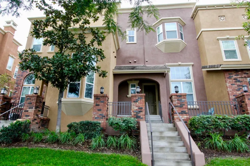 a pleasant day in the domain with a house that has steps in center and tree on the front and garden around