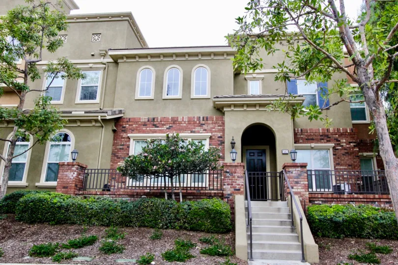 a pleasant day in the domain with a building that has stone walls and steps in center and garden around