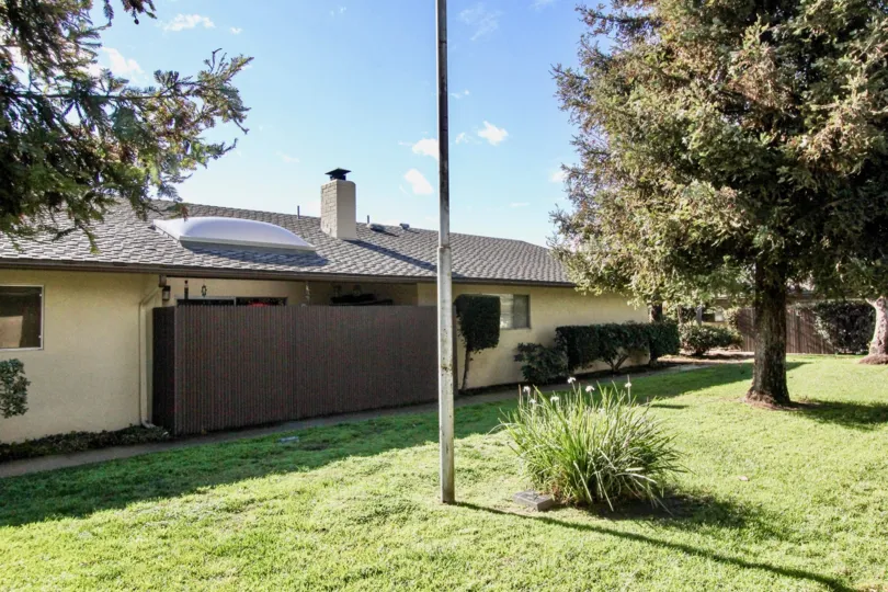 A flagpole in the center of the green yard of a ranch home in The Pines of Anaheim