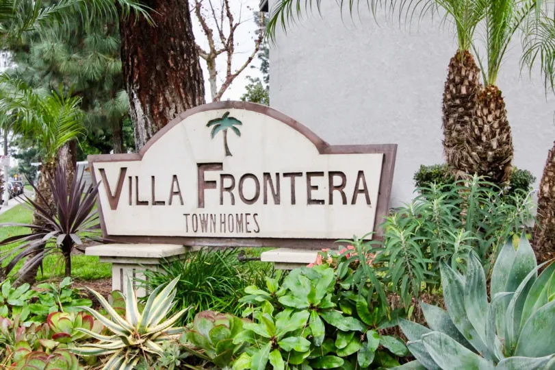 THIS PICTURE SHOWS THE NAME BOARD WITH LOT OF PLANTS LIKE CROTONS, TREES LOCATED IN ANAHEIM CITY