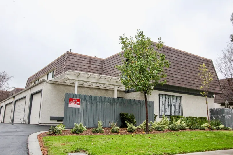 a pleasant day in the village green with a house that has roofless top and parking 2 door closed and garden in the front