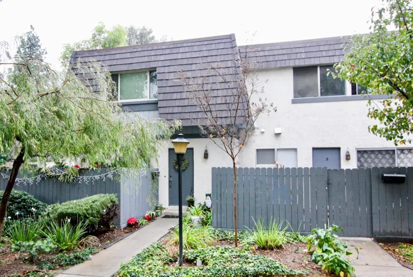 THE FRONT OF THE HOUSE LOCATED IN ANAHEIM, THAT SHOWS THE PLANTS, TREES, LAMP, PATHWAY TO THE HOME
