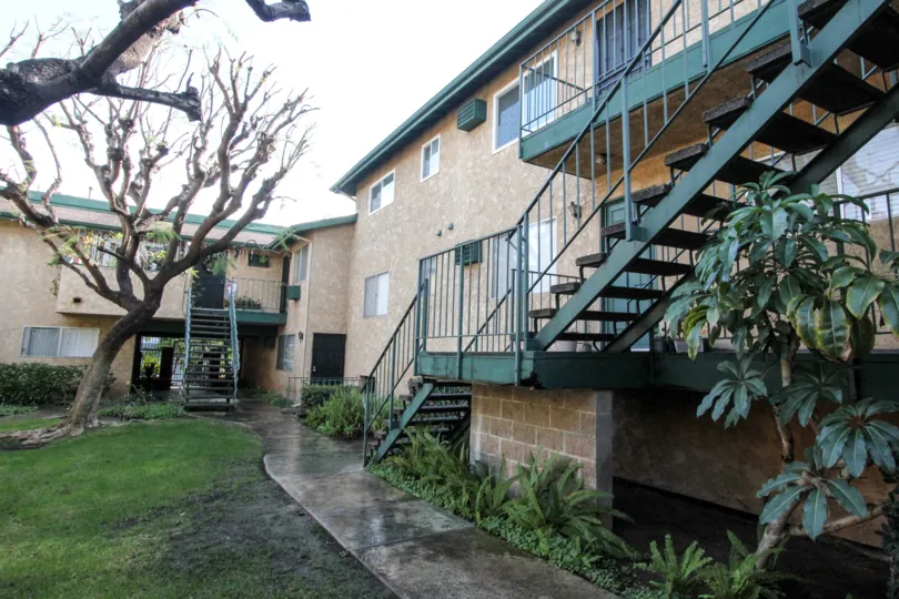 brick grass tree building two story plants sidewalk metal stairs