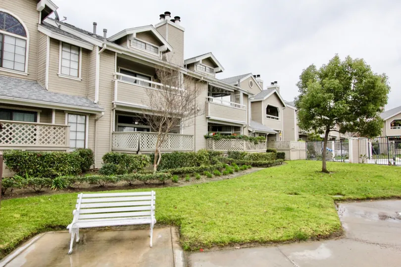 A bench outdoors in a common area in the Wellington Landing community in front of a row of units