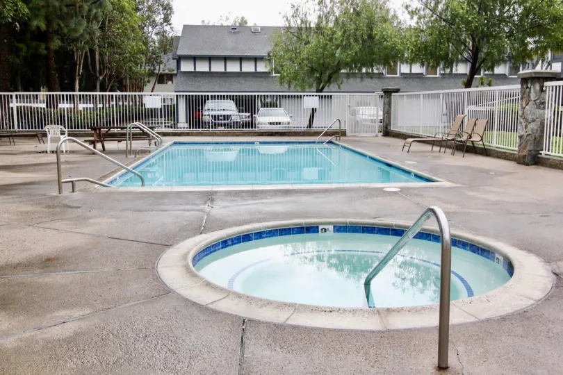 A swimming pool in Wind Rider with some trees and chairs.