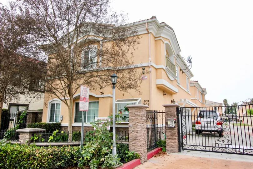 a pleasant day in the buena park villas with a building that has parking car and entrance gate closed and roofless top