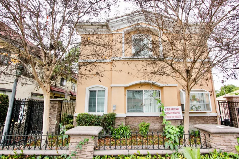 THE BUILDING IN THE BUENA PARK VILLAS WITH THE PLANTS, BENCHES, TREES