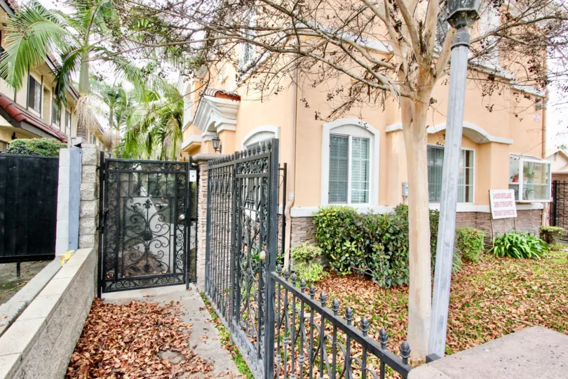 A black gate in the Buena Park VIllas with some trees.