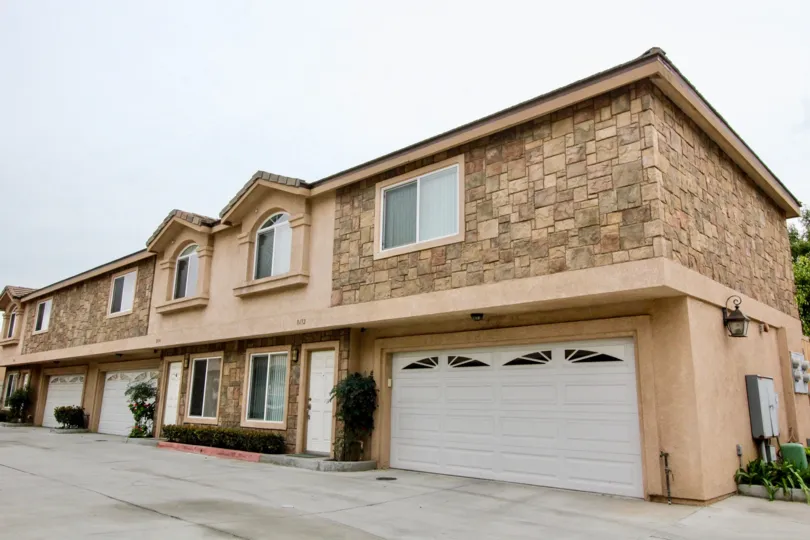 a rainy day in the buena villa town homes with a building that has 3 parking door and garden in front