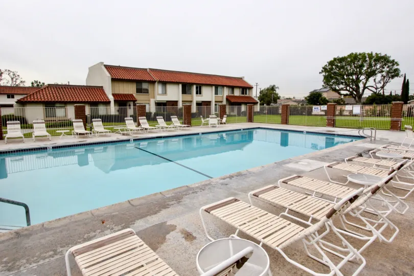 THE SWIMMING POOL IN CASITAS CALIFORNIA, THAT HAVE LOT OF CHAIRS SURROUNDED THE WALL BEHIND THE TREES