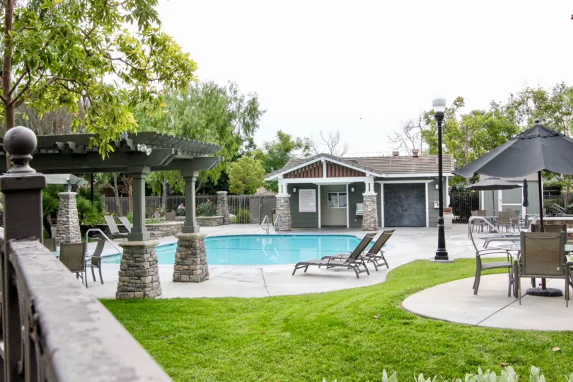 THIS IMAGE SHOWS THE BEAUTIFUL SWIMMINGPOOL IN BUENA PARK THAT HAVE THE LOT OF CHAIRS, LAWN, TREES AND PLANTS