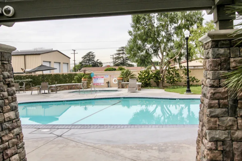 a pleasant day in the college park with a building that has swiming pool and 2 stone walls and cctv camera