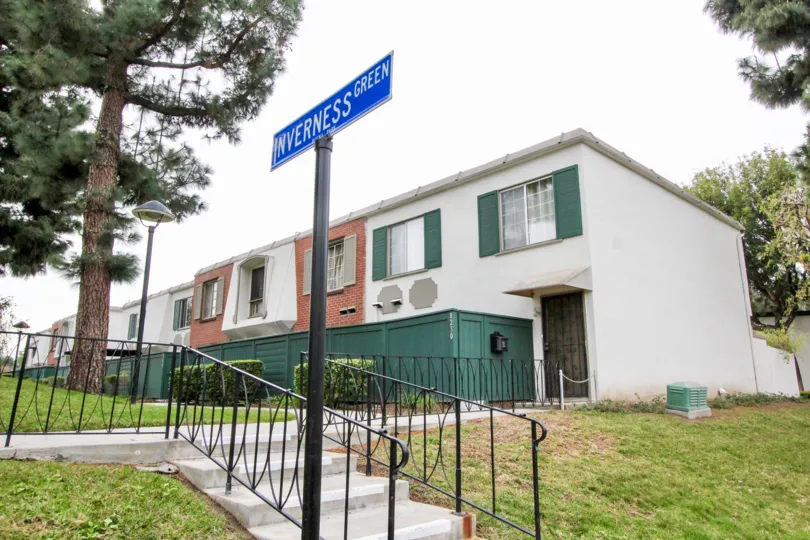 THIS IMAGE VIEWS THE ENTRANCE WAY IS LOCATED IN BUENA PARK, THAT SHOWS THE NAME BOATD, FULLY LAWN, TREES ARE THERE