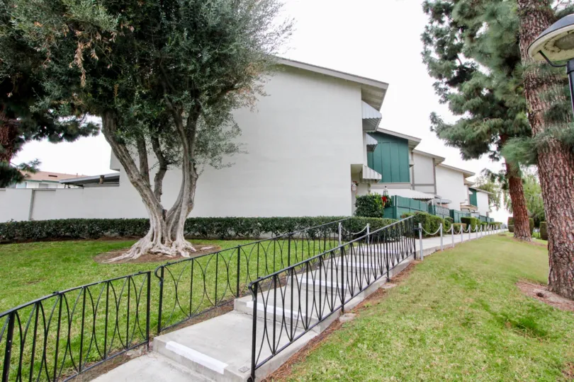 THIS IMAGE VIEWS THE SIDEVIEW OF THE FLATS WITH LAWN, TREES, PATHWAY WHICH IS LOCATED IN BUENA PARK