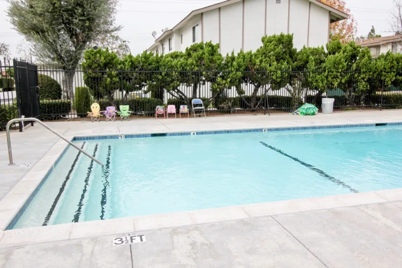 THIS IMAGE SHOWS THE SWIMMING POOL WITH MARKS ON THE FLOOR, NEARBY PLANTS, TREES ARE THERE IN BUENA PARK