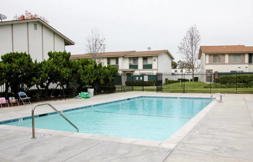 A blue color swimming pool Highland Greens with some chairs.
