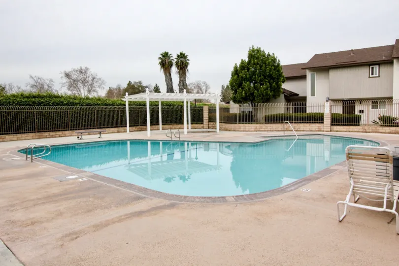 A cloudy day in the Summertree with a swimming pool and chair.