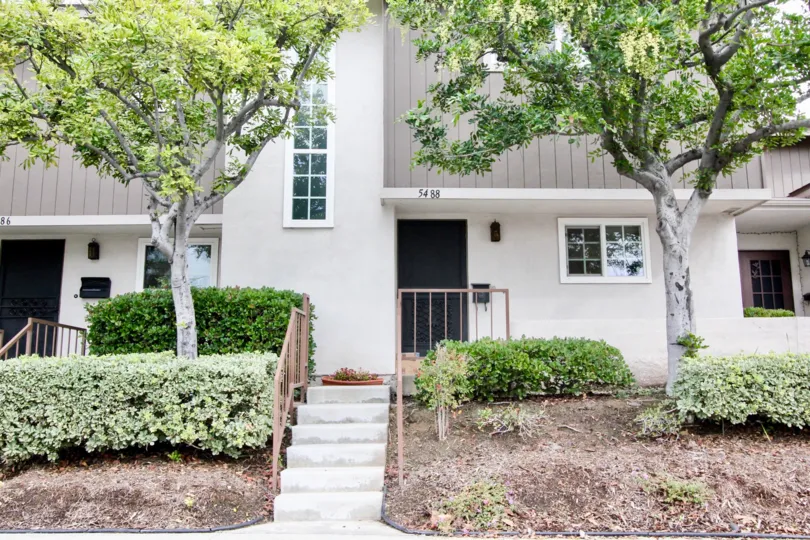 a rainy day in the summer tree with a house that has numbered as 5483 and steps in center and two trees in front and garden around