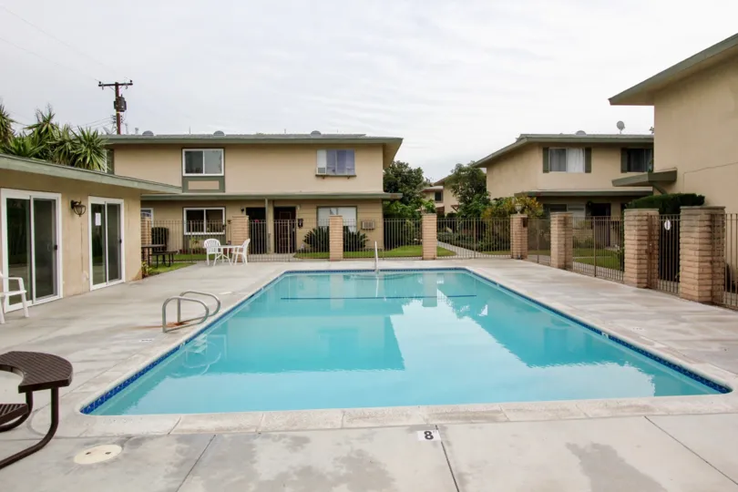 THIS IMAGE VIEWS THE HOME AROUNDBY SWIMMING POOL IN BUENA PARK THAT HAVE THE LAWN, AND SMALL PLANTS, TREES