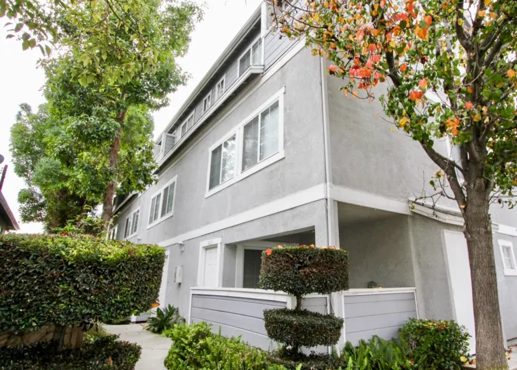 THE SIDEVIEW OF THE VILLAS WITH CROTON PLANTS, TREES ARE LOCATED IN BUENA PARK