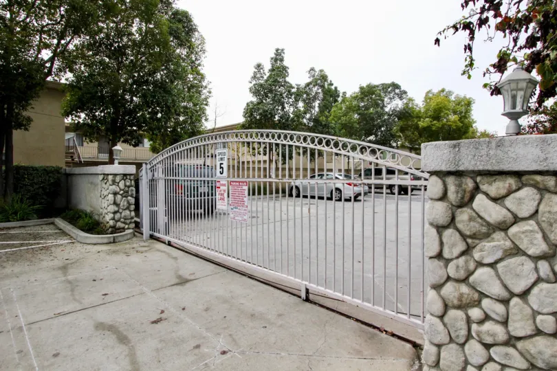 a rainy day in the western bay estates with a building that has parking car and entrance gate closed and stone walls