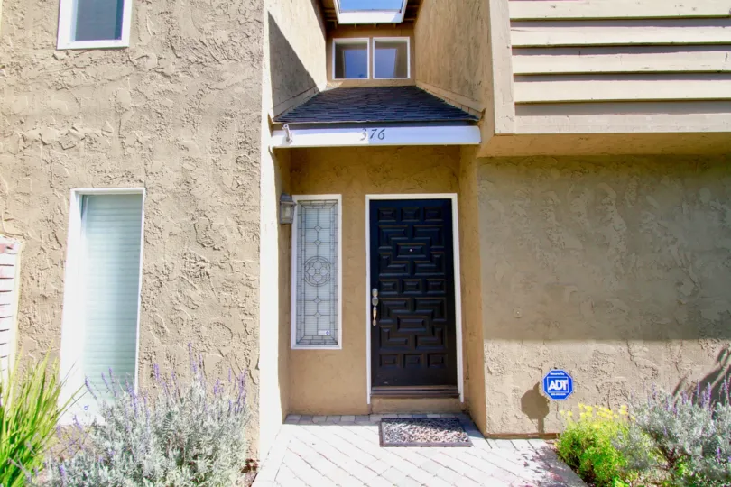 Back Bay Village Sunrise door to a home with windows and plants.