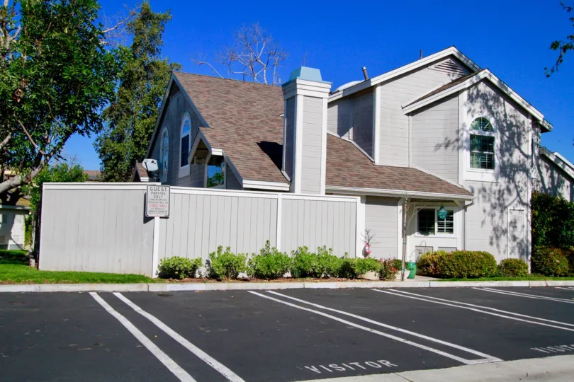Woodstream Condos home with a fence and parking spaces on a sunny day.