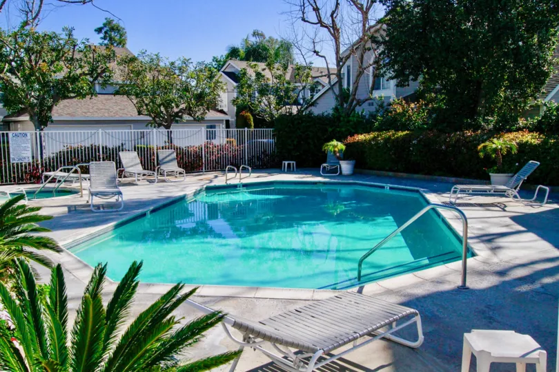 THE SWIMMING POOL WITH RELAXATION SITTING PLACES AND A COT ALSO AVAILABLE SOME TREES ALSO NEAR TO THE POOL ANS SUNSHINE AT THE POOL.