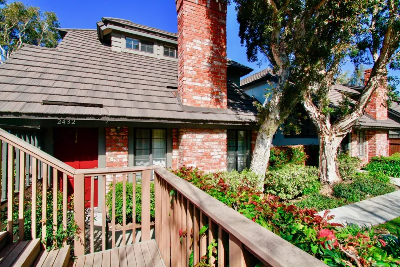 The home in the Brittanywoods is like a cottage house with lots of green plants and trees with wooden grills.