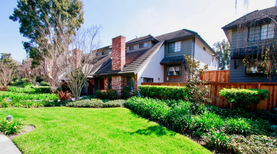 The home in the Brittanywoods is like a cottage with lawn, trees and green plants.