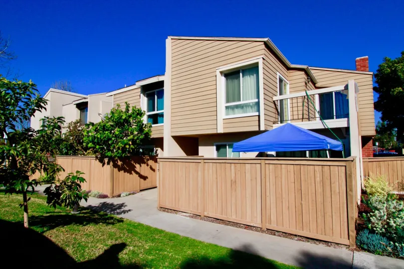 Brookview apartments with a wooden fence and trees on a sunny day.