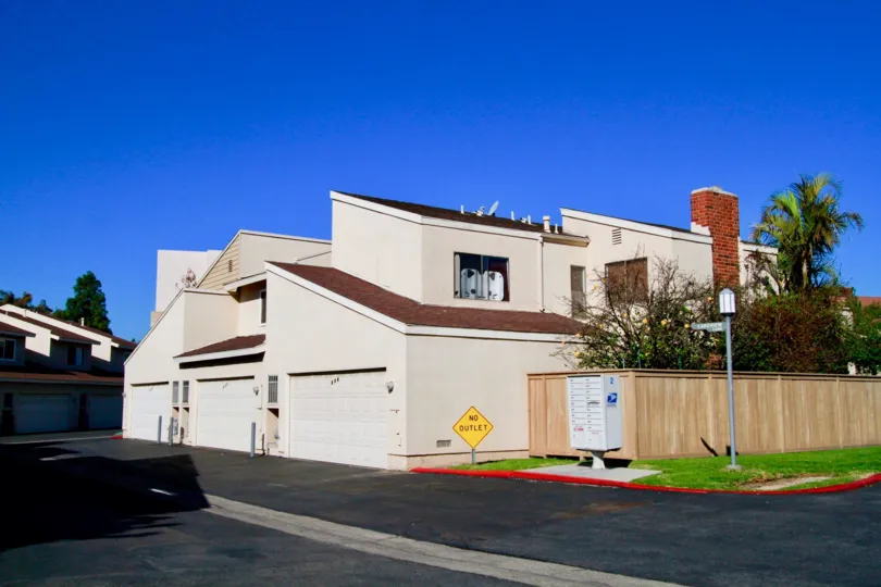 Multiple eaves, sloping roofs, brick chimney, high privacy fence, surrounding palms, mark Brookview home, Costa Mesa, California