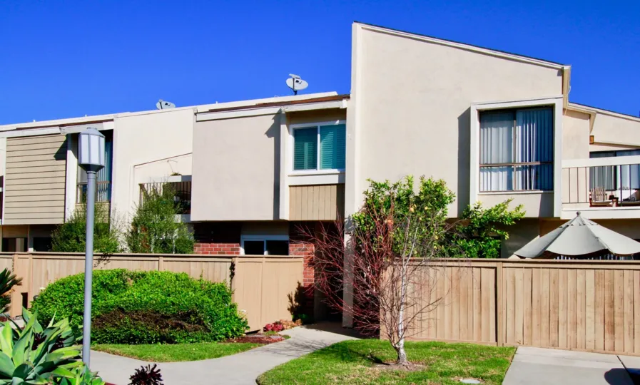 Brookview apartments with a wooden fence and trees on a sunny day.