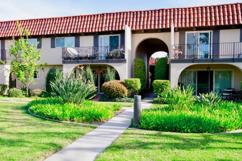 Country Club Villas two story apartments with a sidewalk on a sunny day.