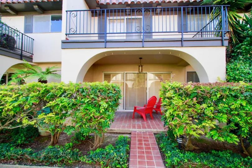 Country Club Villas apartments with red deck chairs and bushes.